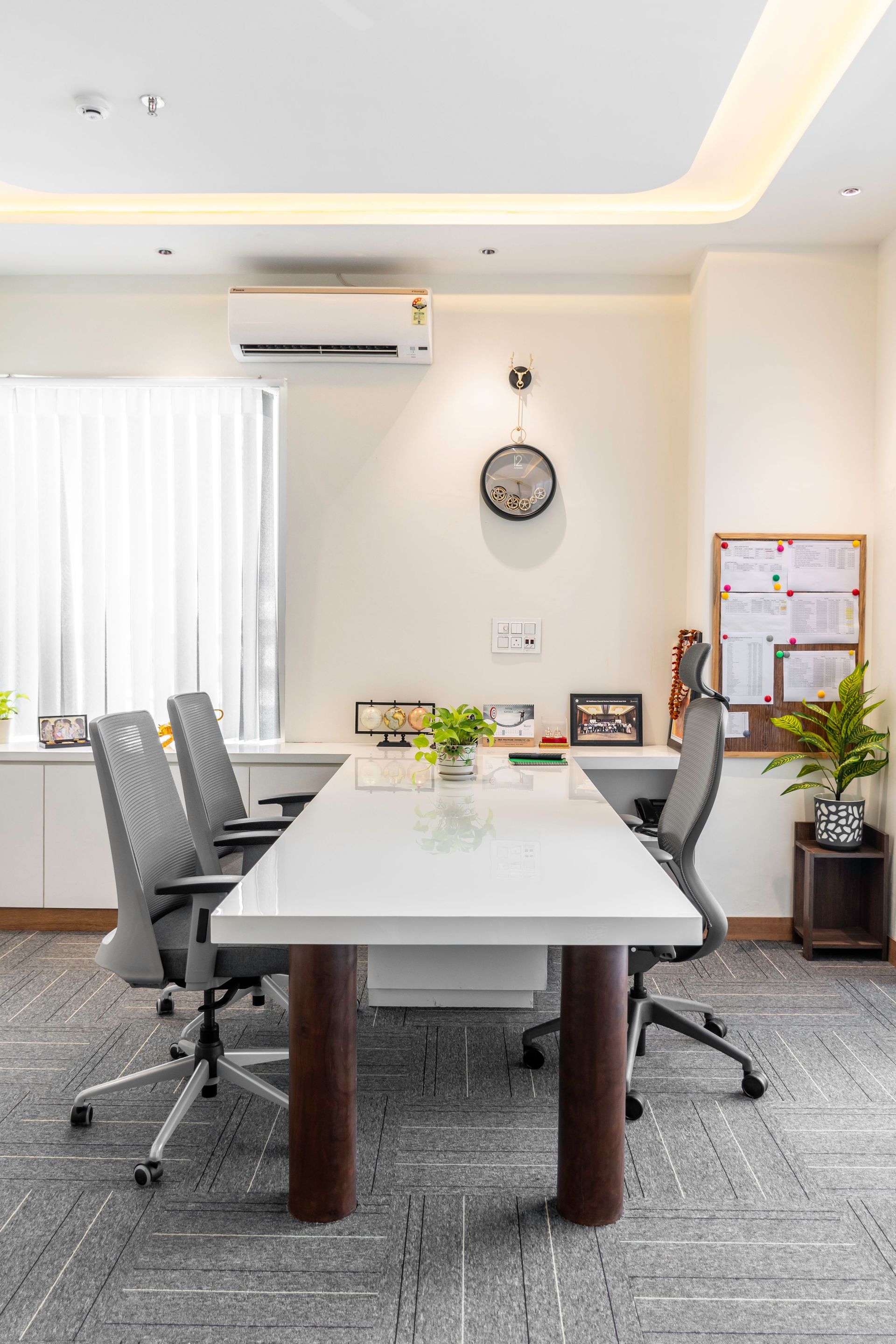 Bright and minimalist conference room with white table and grey chairs.